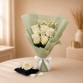 Ivory Vow - six ivory white roses with baby's breath in sage green wrap with a white satin bow, beside a single ivory rose on a black velvet cushion