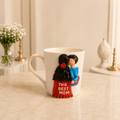 Mother's Rose Mug - white ceramic mug sculpted with a mother in a red top lettered THE BEST MOM holding a child in blue