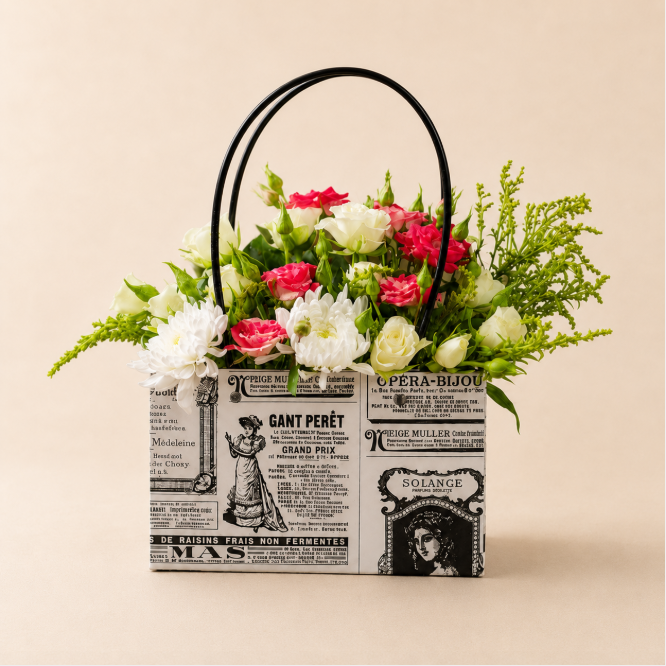 Chic Bloom Basket — pink and white flowers in a vintage newspaper-print basket with black handles, Velvety Flowers